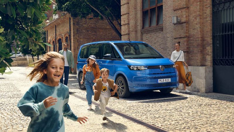 Blå VW Multivan eHybrid familjebil med en familj