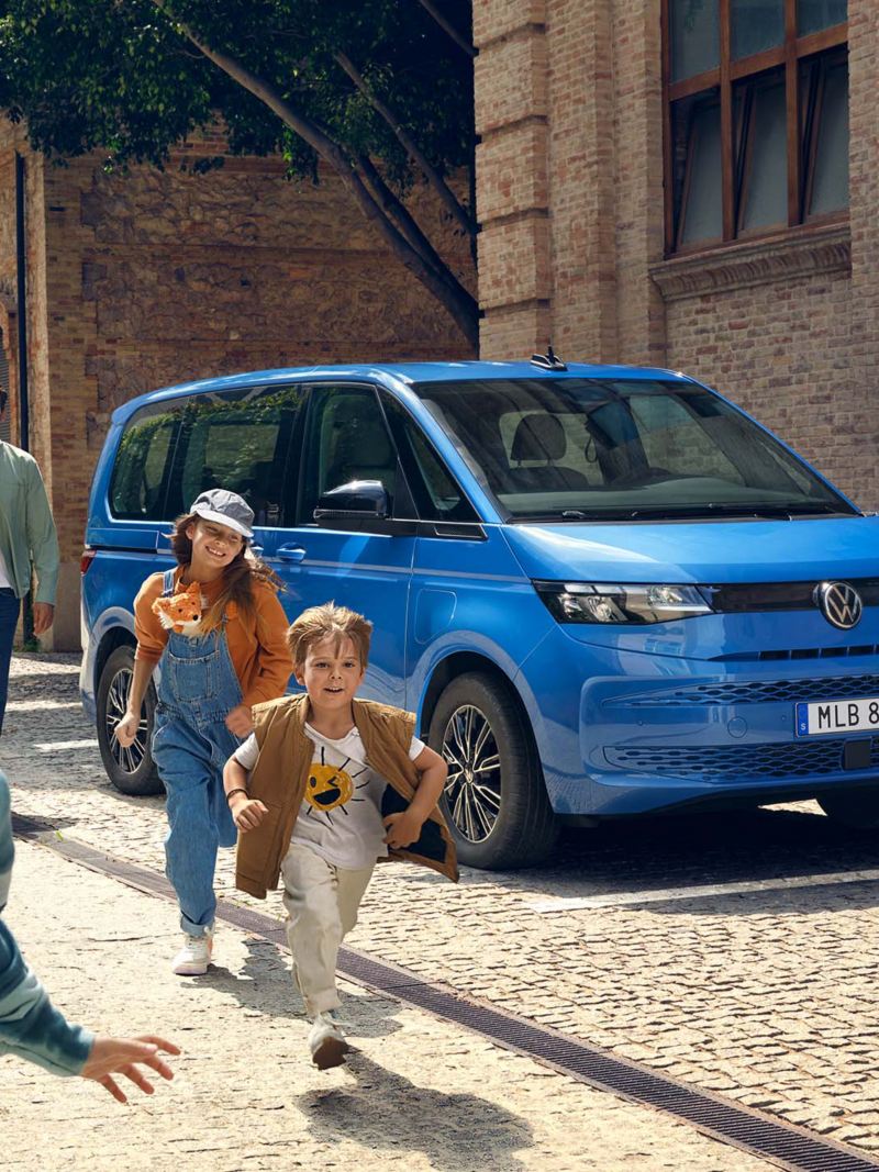 Blå VW Multivan eHybrid familjebil med en familj