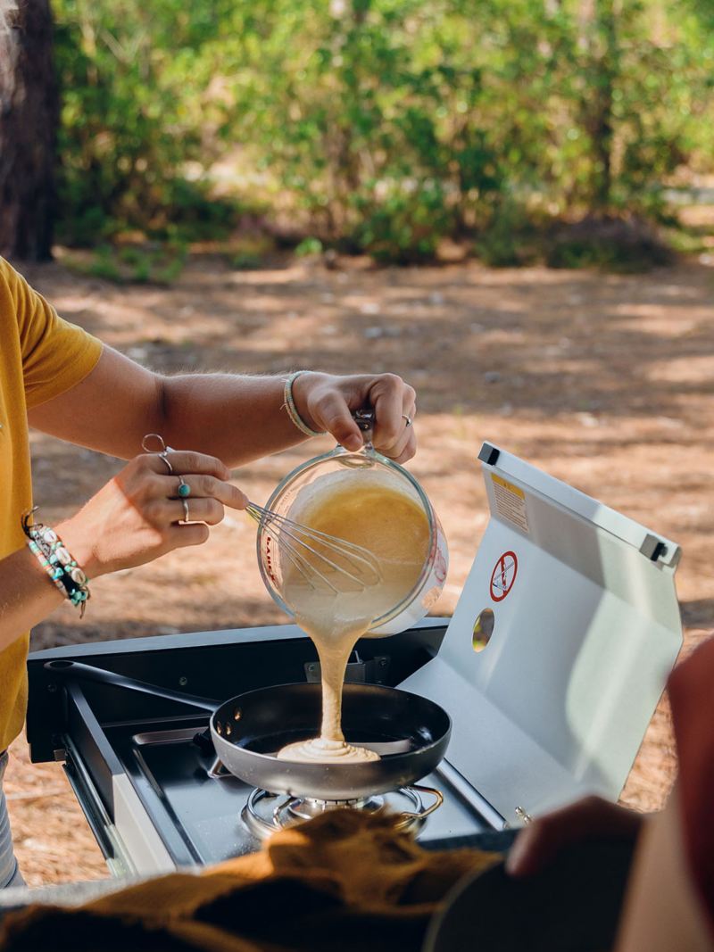 Två kvinnor lagar mat vid en VW Caddy California campingbil