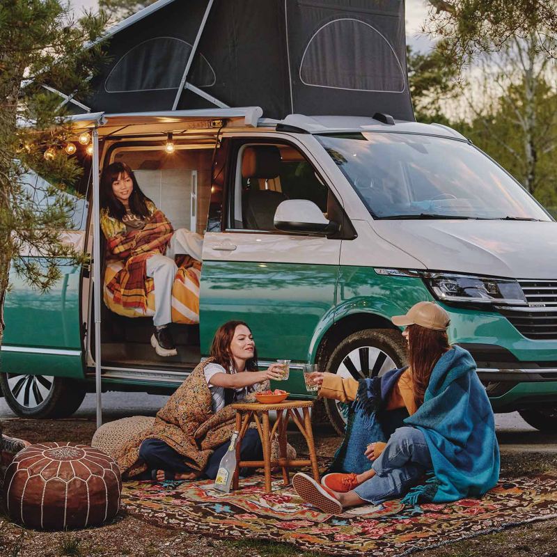 Kvinnor campar utanför en VW California 6.1 campingbil