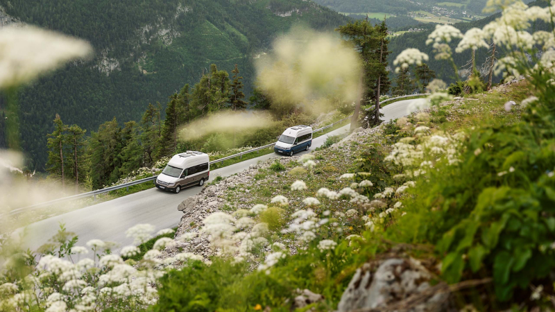VW Grand California kör längs en landsväg i bergsmiljö