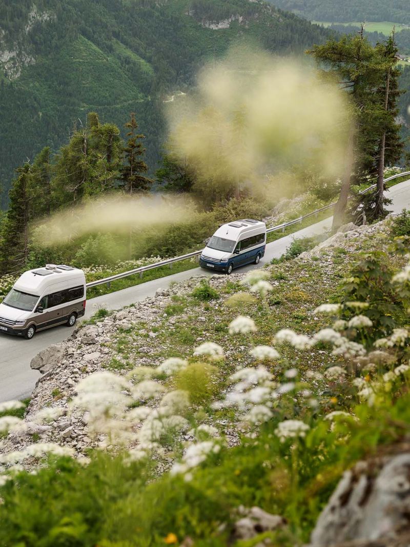Två VW Grand California kör i bergsmiljö