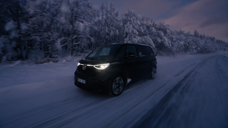 En svart VW ID. Buzz Cargo kör på en vinterväg