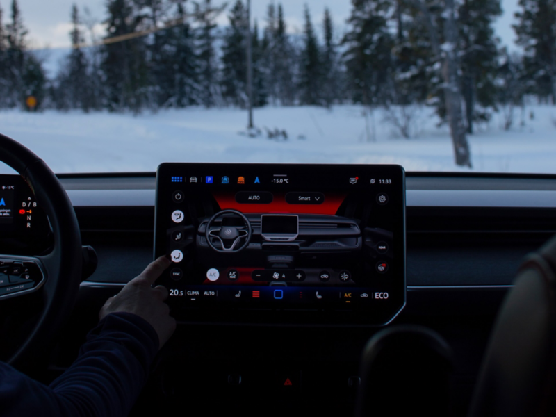 En hand styr klimatanläggningen via touchskärmen på en VW ID. Buzz