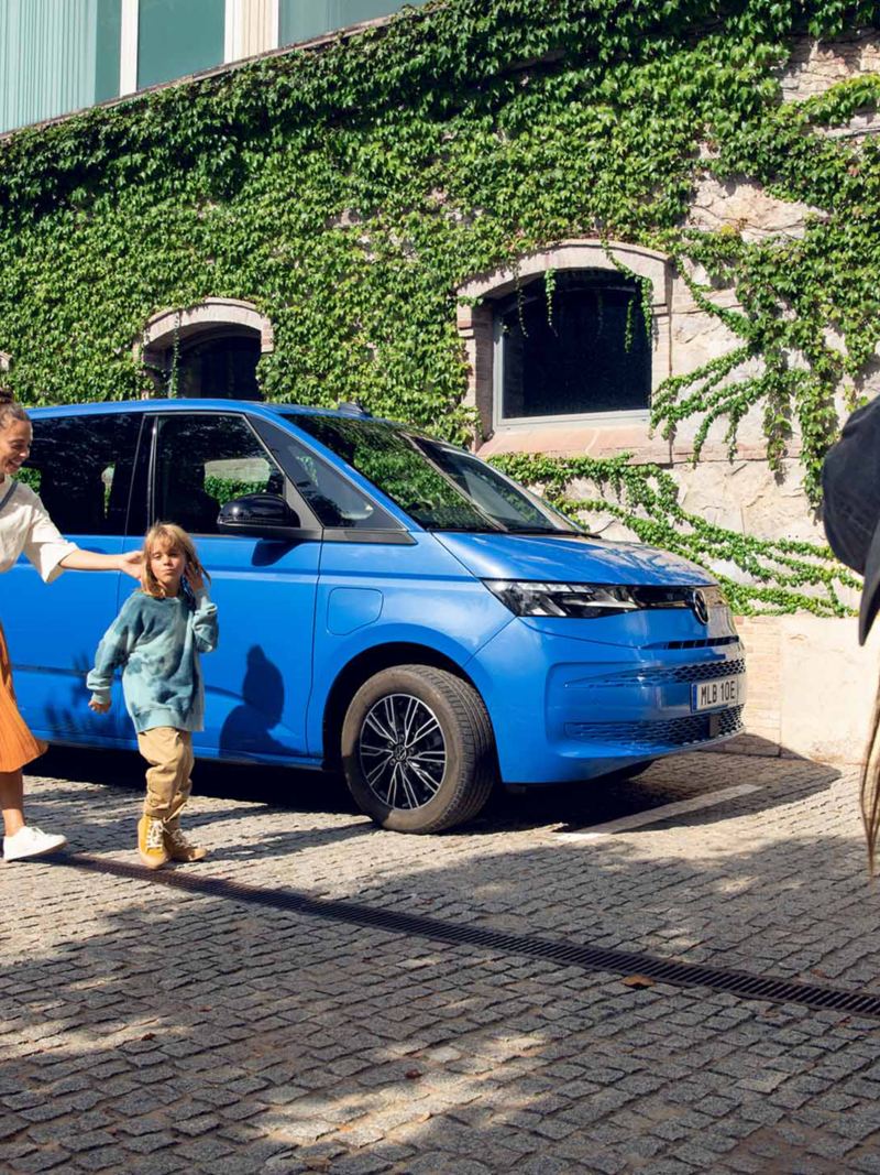 Familj vid en blå VW Multivan eHybrid minibuss