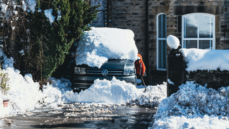 En snötäckt VW Multivan står parkerad vid ett hus