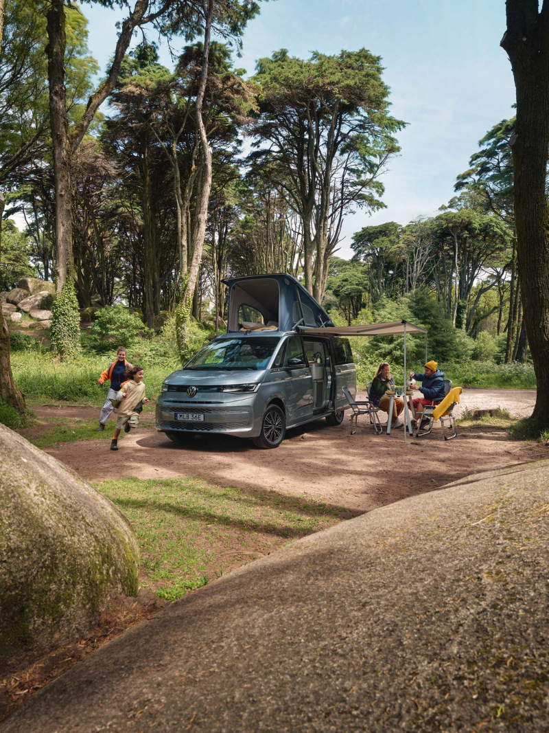 Två VW California campingbussar uppställda med sidodörrar och popup-tak öppna.