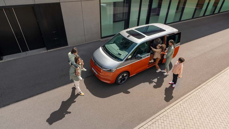 Familj framför nya tvåfärgade VW Multivan laddhybrid minibuss