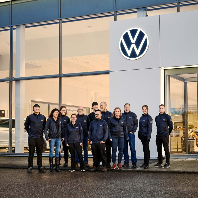 Personal från Team transportbilar uppställda framför ett VW showroom