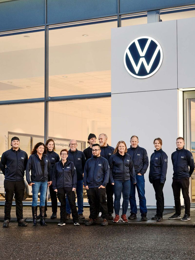 Personal från Team transportbilar uppställda framför ett VW showroom