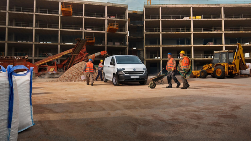 Trabajadores caminando frente al Nuevo Transporter 2025 en una construcción