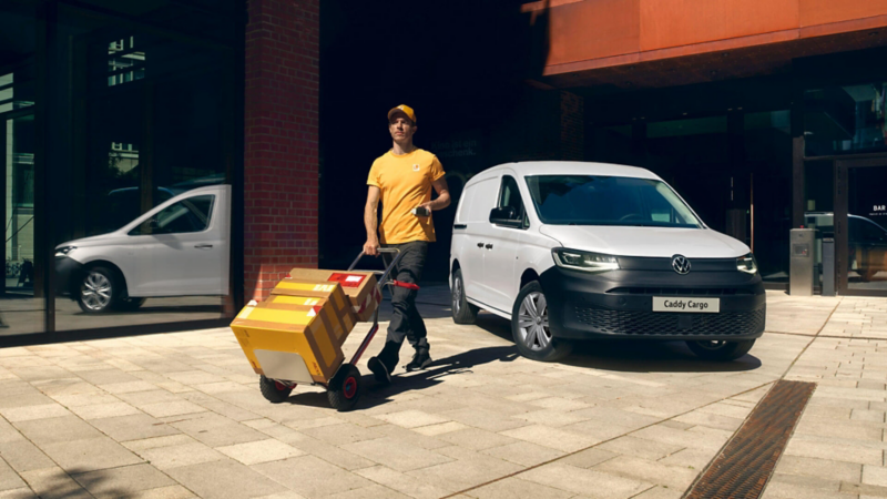 Encargado de reparto entregando paquetes en un Caddy Cargo de Volkswagen