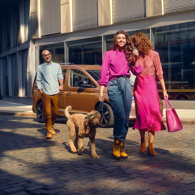 Familia haciendo compras con un vehículo familiar VW Caddy en el fondo