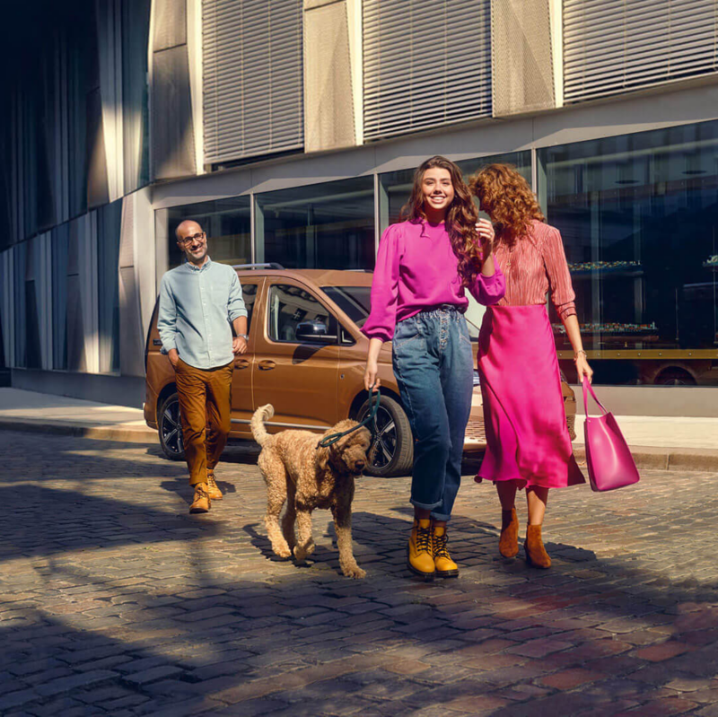 Familia haciendo compras con un vehículo familiar VW Caddy en el fondo