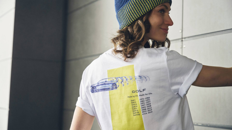 Colección de ropa y accesorios de Volkswagen con modelos de autos clásicos. Niño sentado en plegable con diseño de Combi.