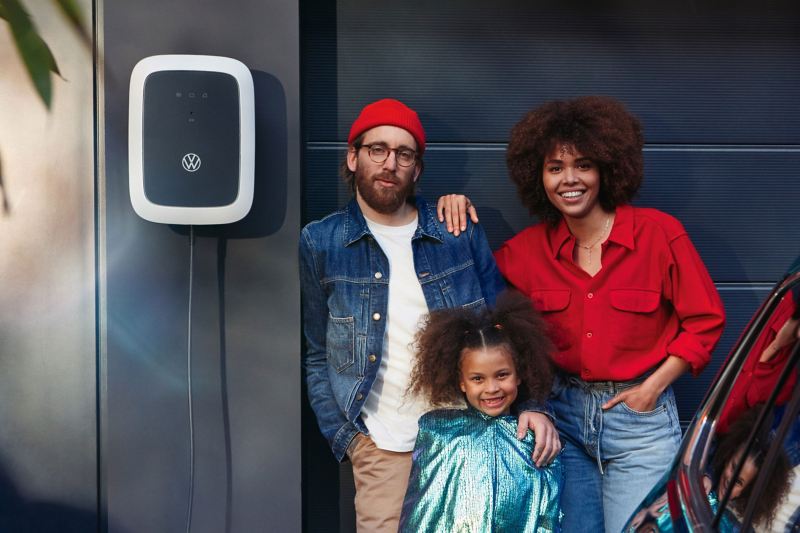 Eine Familie steht vor ihrer Garage, an der Wand ist ein ID Charger angebracht.