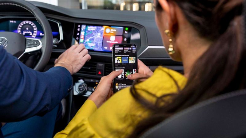 Mujer con celular elige canción con aplicación conectada a camioneta SUV con Wireless App Connect.