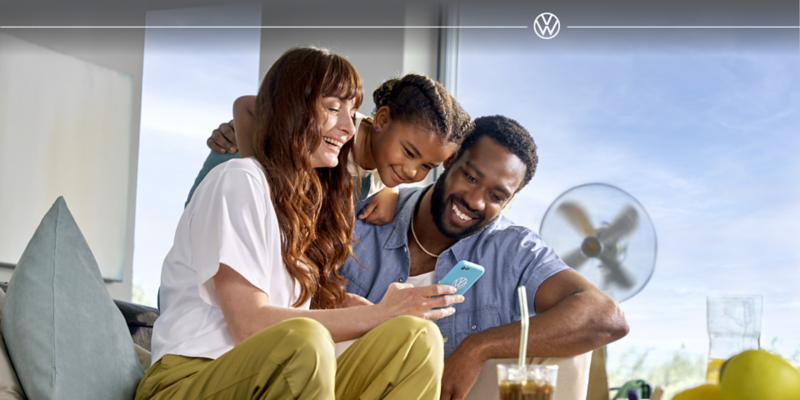 A mom, dad, and young daughter smiling at a phone 