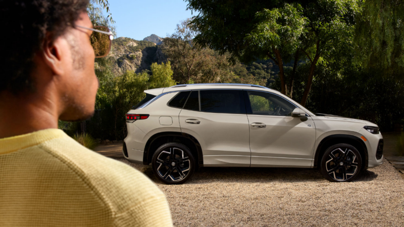 A man photographed from behind, looking at a white car, photographed from behind 