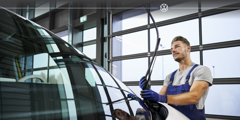 A mechanic focused while working on a white car