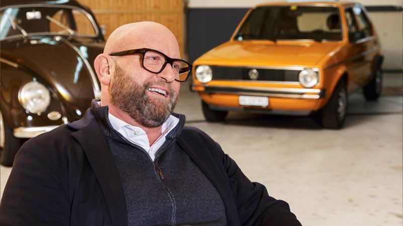 Claude Gregorini lacht vor alten VW Modellen