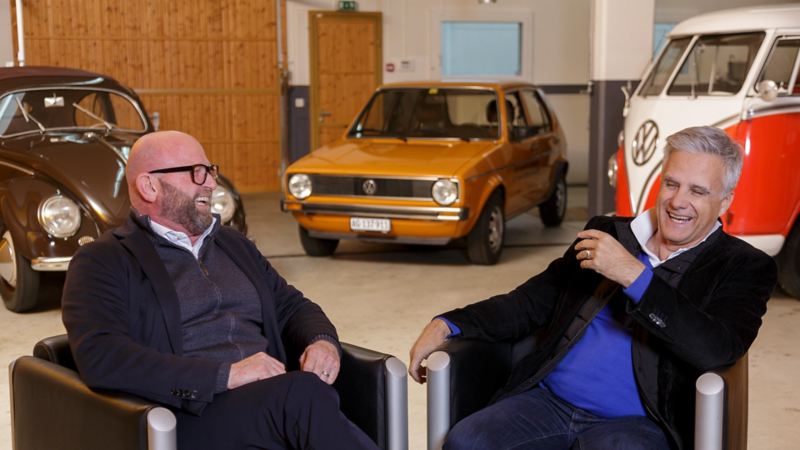 Claude Gregorini und Dino Graf lachen vor alten VW Modellen