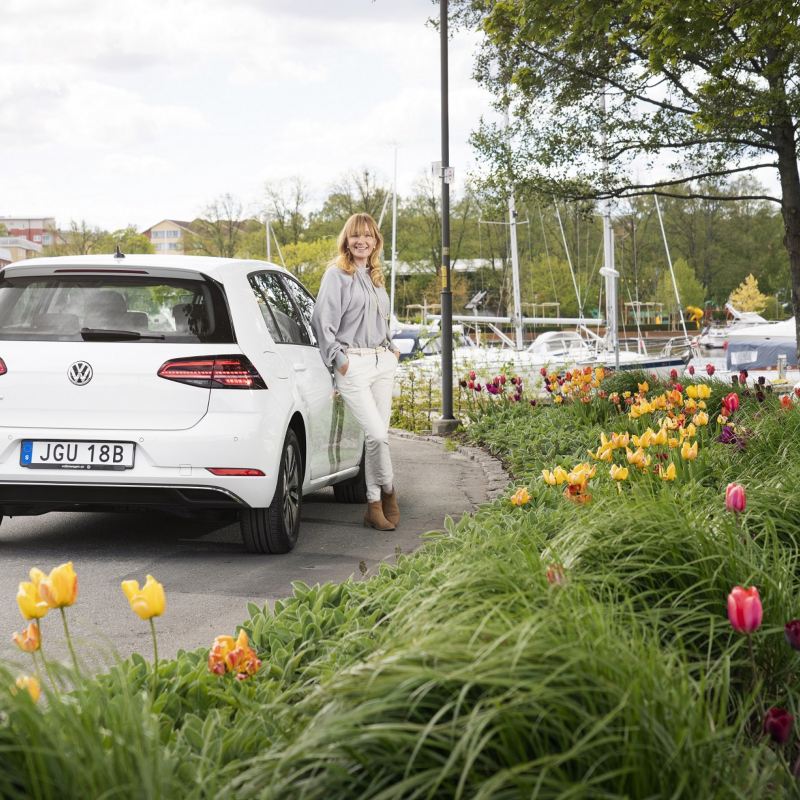 Kvinna står lutad mot Volkswagen e-Golf