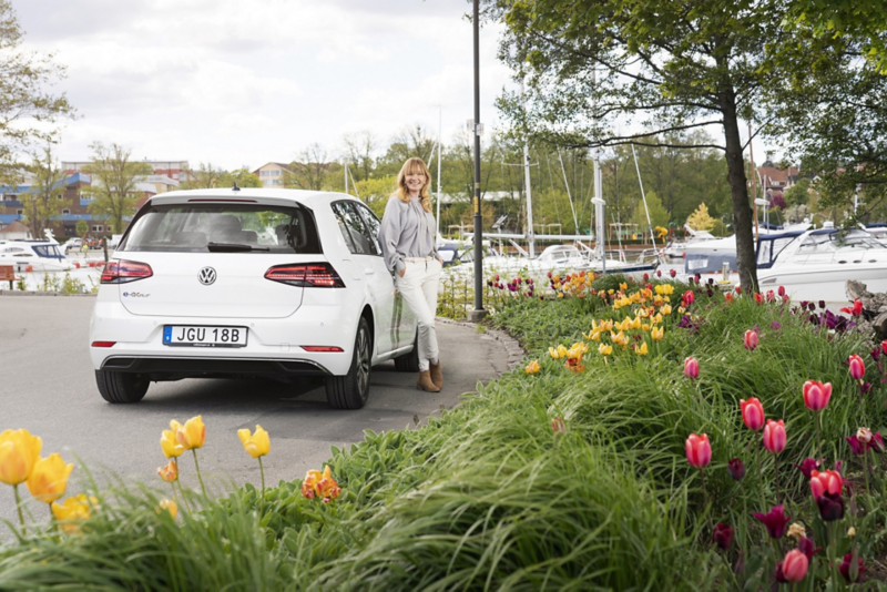 Kvinna står lutad mot Volkswagen e-Golf