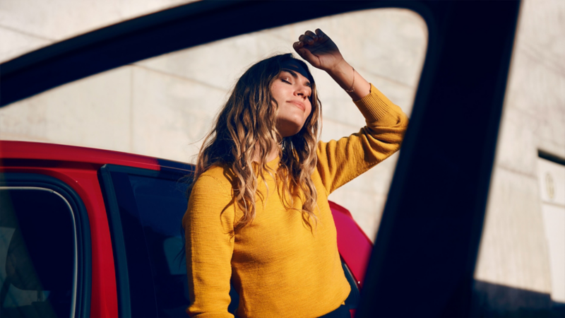 Eine Frau steht in der Sonne vor einem Volkswagen