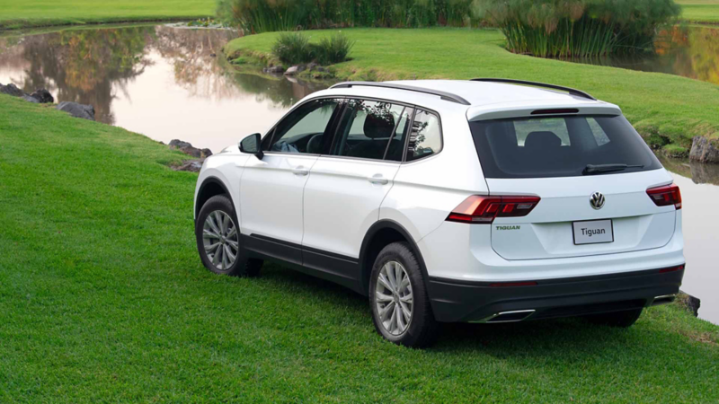 Camioneta Tiguan de color blanco cerca de un pequeño río dentro de un jardín.