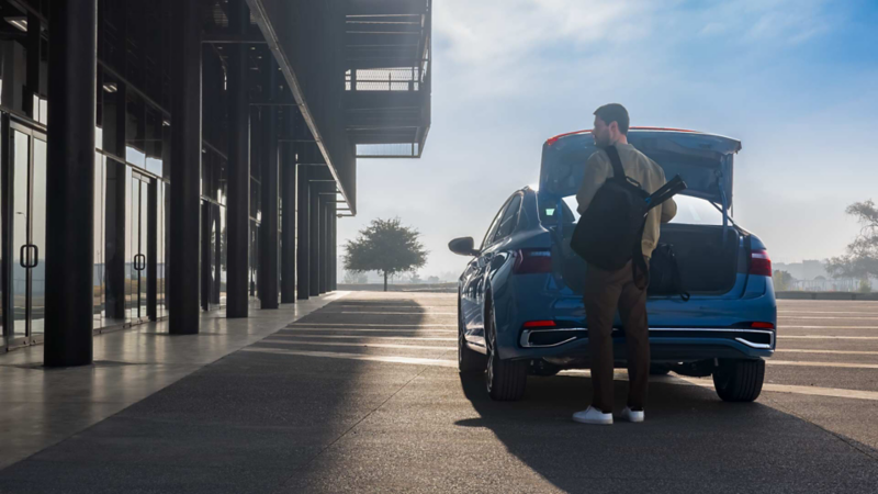Conductor de Volkswagen Jetta mete mochila a cajuela de sedán. 