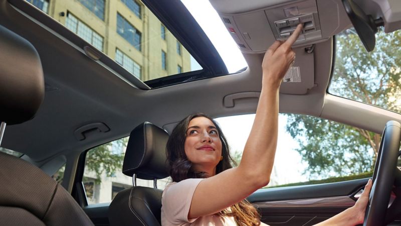 Woman in vehicle opening sunroof 