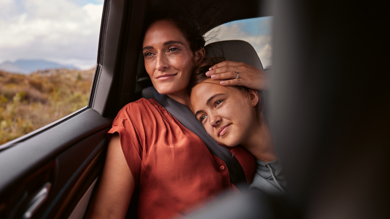 Two people sitting closely in the back of a vehicle