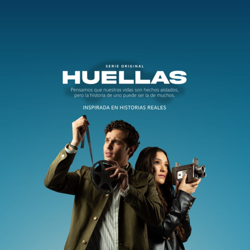 Pareja con cámara y rollo de película encima de fondo azul y logotipo de Huellas.