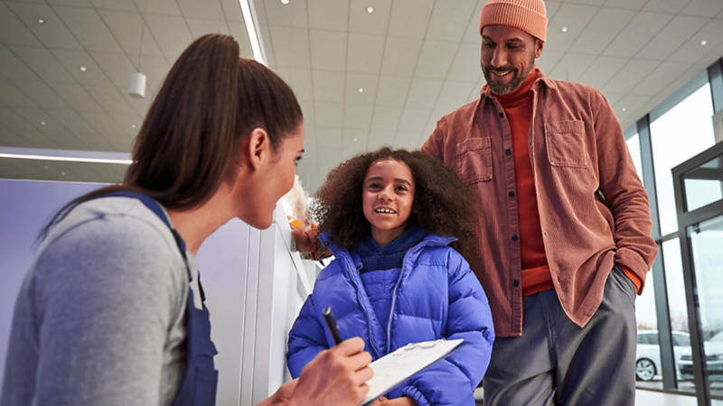 Un père et sa fille parlent à une représentante du service à la clientèle VW