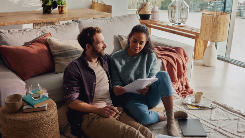 Un couple est assis par terre et lit des documents