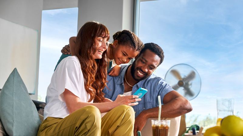 A family looking at a mobile phone with a VW phone cover