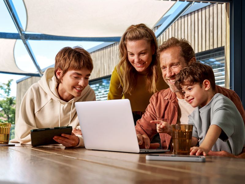 A family sitting at a table looking at a laptop