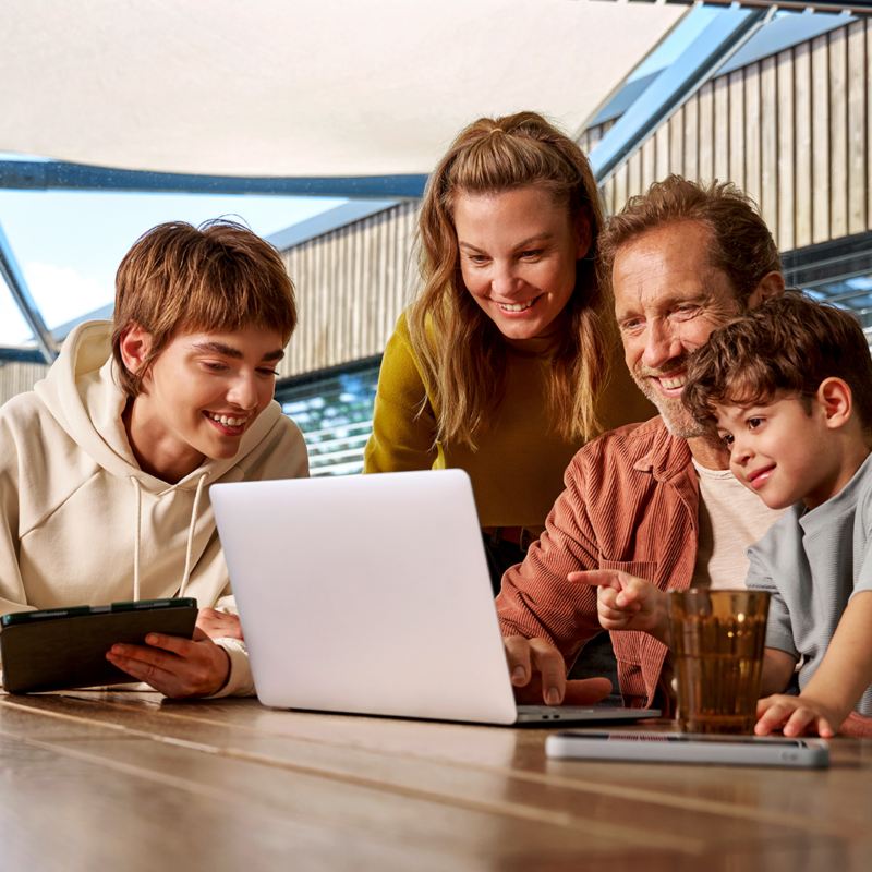 A family sitting at a table looking at a laptop