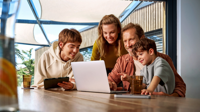 A family sitting at a table looking at a laptop