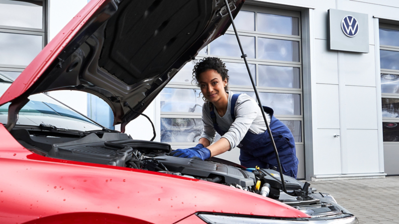 Une technicienne VW travaille sous le capot d’une VW