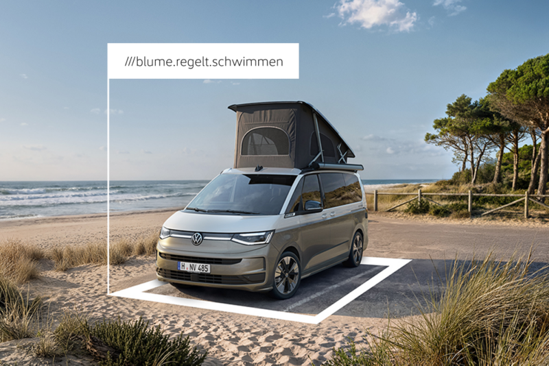 Ein VW California mit aufgestelltem Aufstelldach steht auf einem Parkplatz am Strand. Ein eingeblendetes Quadrat markiert den Standort mit der dazugehörigen what3words-Adresse.