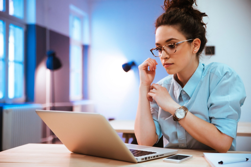 Joven mujer observa una computadora mientras busca datos. 
