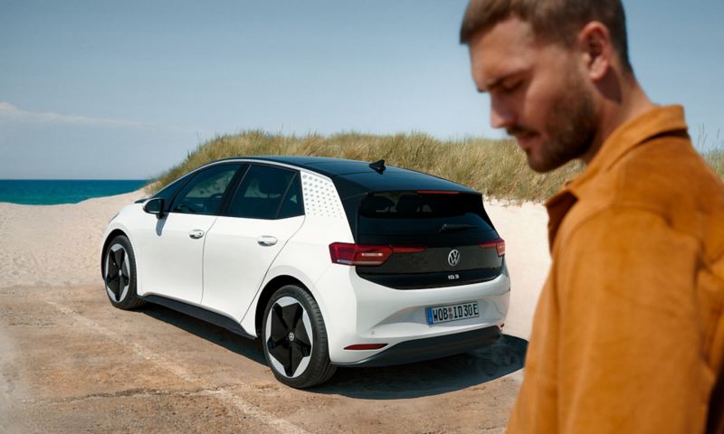 Man on the beach, in the background the VW ID.3.