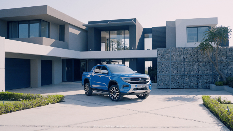 En blå VW Amarok Aventura generation 2 parkerad framför ett stenhus