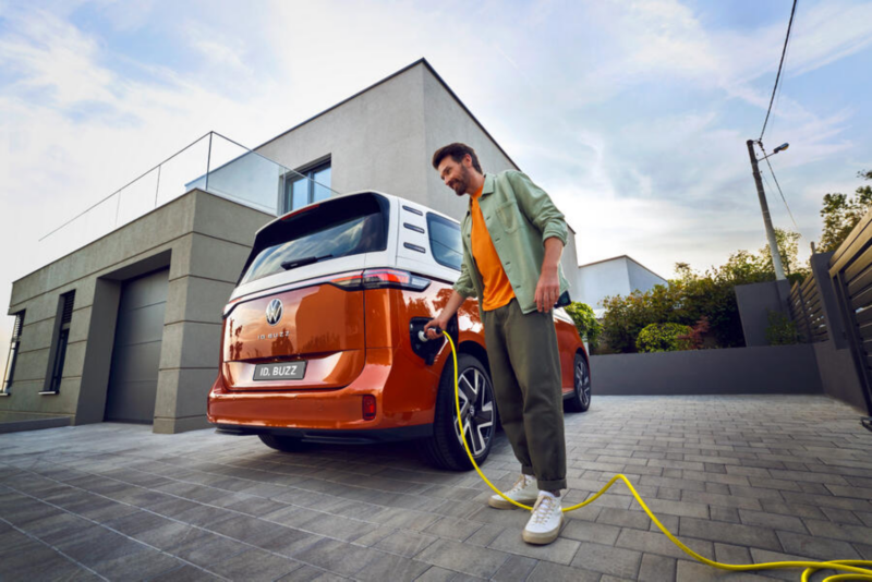 Męzczyzna podłącza VW ID. Buzz  z boku do stacji ładowania.