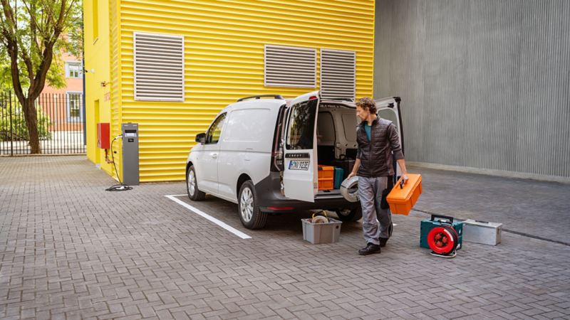 Hantverkare står bakom en VW Caddy Cargo eHybrid laddhybrid med öppet lastutrymme