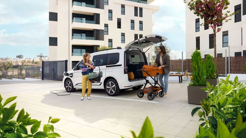 Barnfamilj står bredvid en vit VW Caddy eHybrid laddhybrid