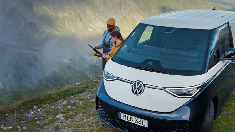 Två personer bredvid en VW ID. Buzz Cargo uppe på ett berg.