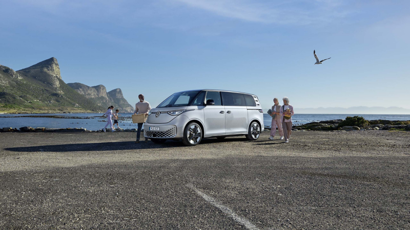 En silvrig VW ID. Buzz el familjebil står parkerad vid havet